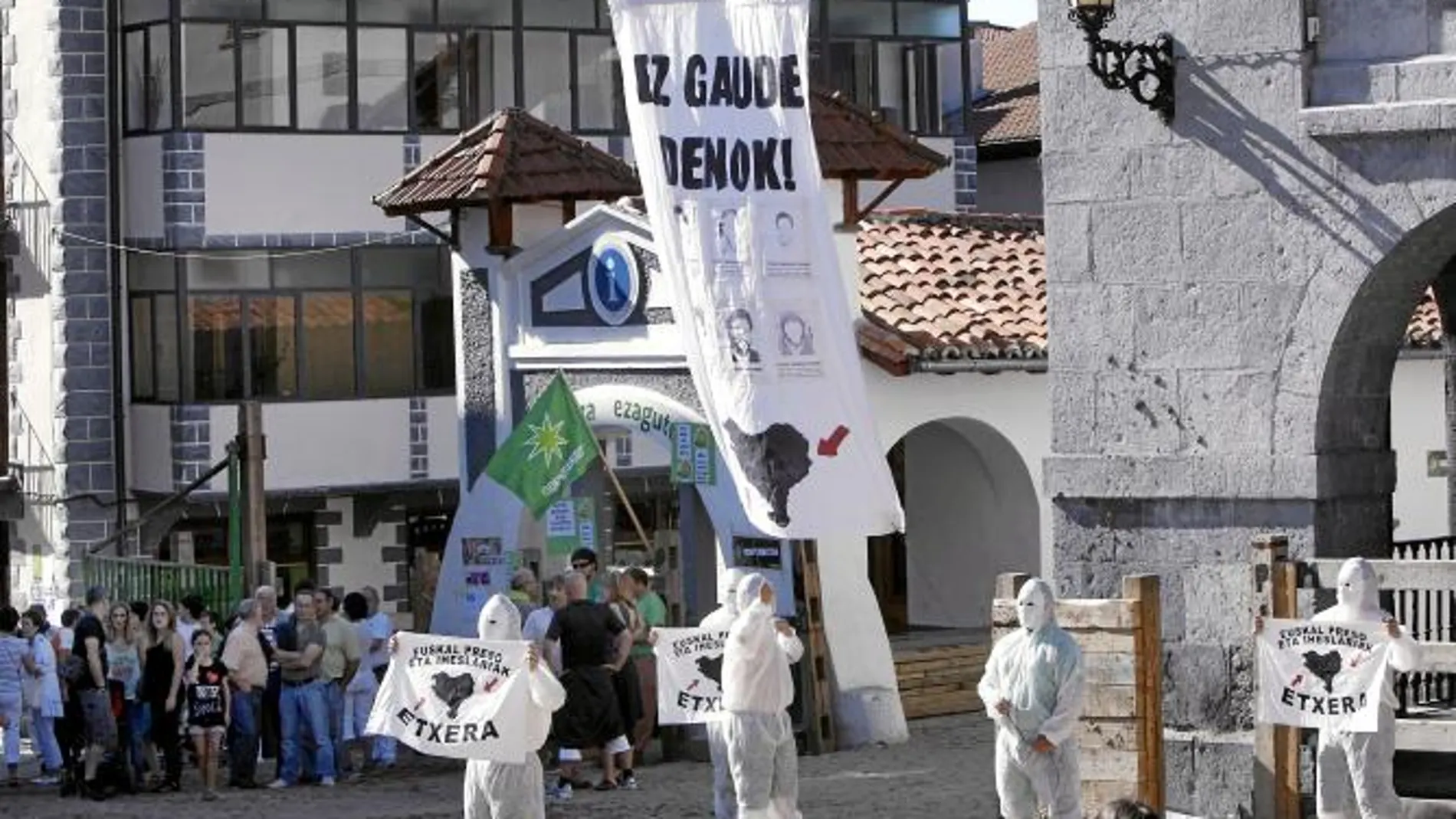 En la imagen, los encapuchados entran en la plaza del pueblo navarro con carteles en favor de los presos etarras.