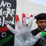 Un rebelde libio muestra sus manos con los colores libios tras hacer un mural que dice: "No más sangre"en Trípoli
