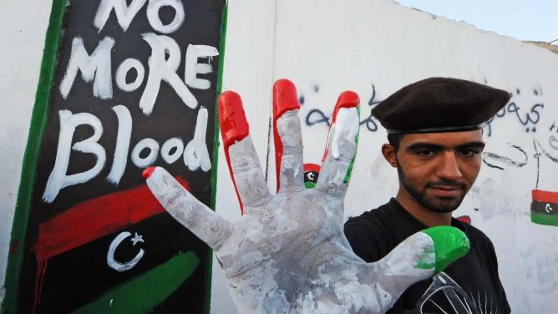 Un rebelde libio muestra sus manos con los colores libios tras hacer un mural que dice: "No más sangre"en Trípoli
