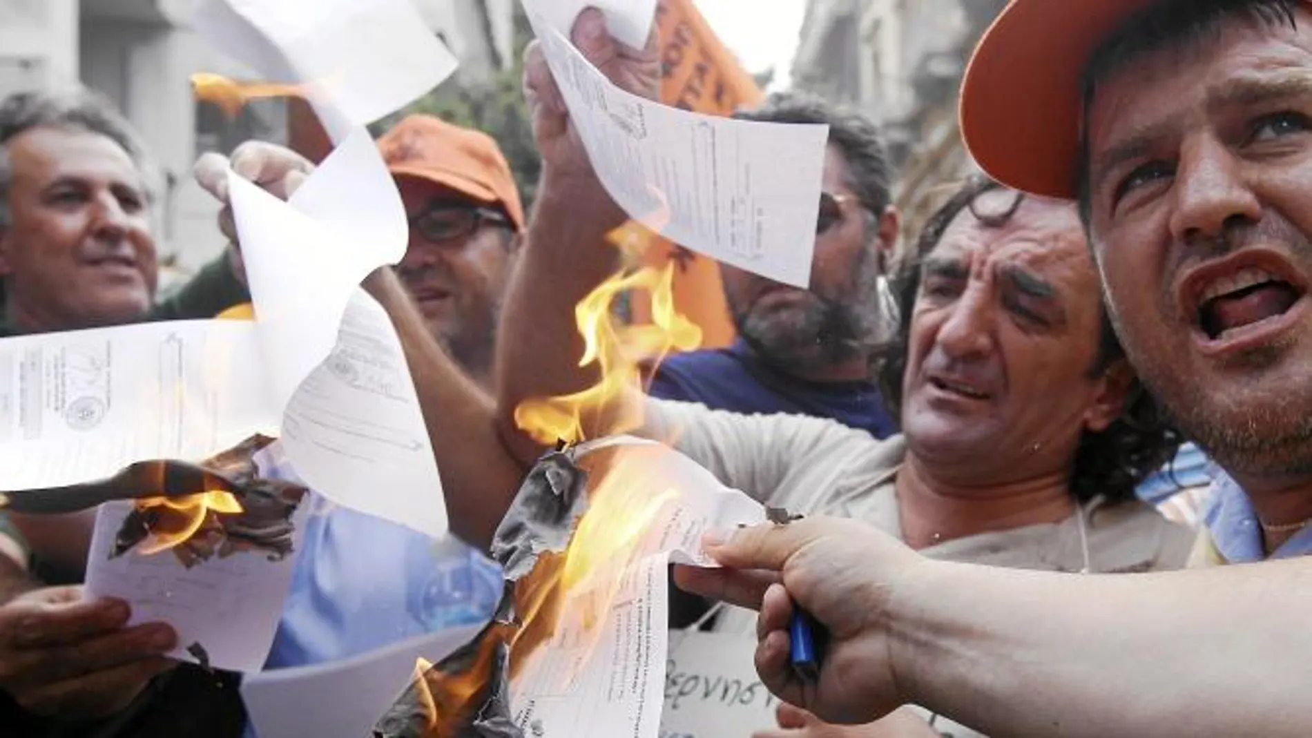 Funcionarios civiles quemaron ayer notas de pago de un impuesto en protesta por el plan de austeridad del Gobierno