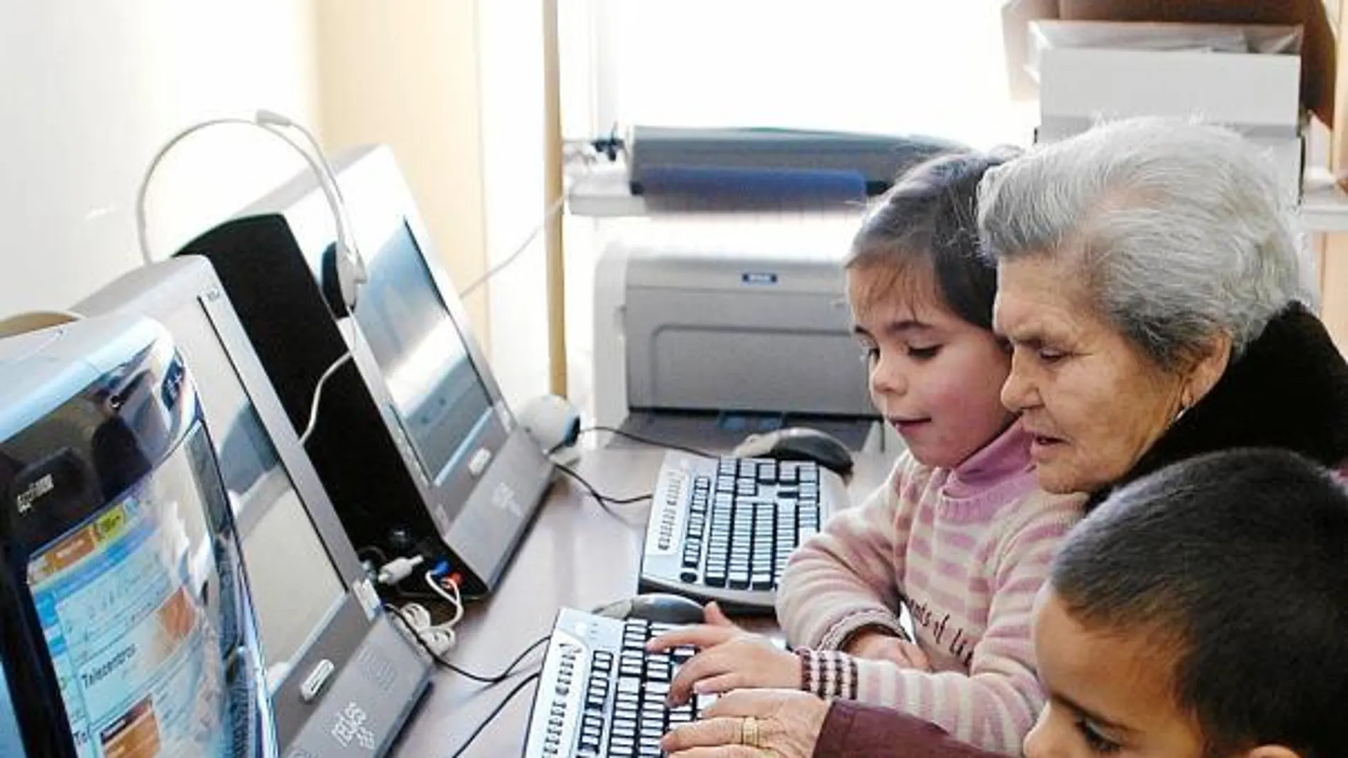Unas vecinas de Villaharta (Córdoba), con sus nietos, aprenden a utilizar el ordenador gracias a un proyecto de la diputación de Córdoba