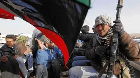 Un rebelde libio observa cómo la población celebra la recuperación de la ciudad de Ajdabiya tras vencer a las tropas gadafistas