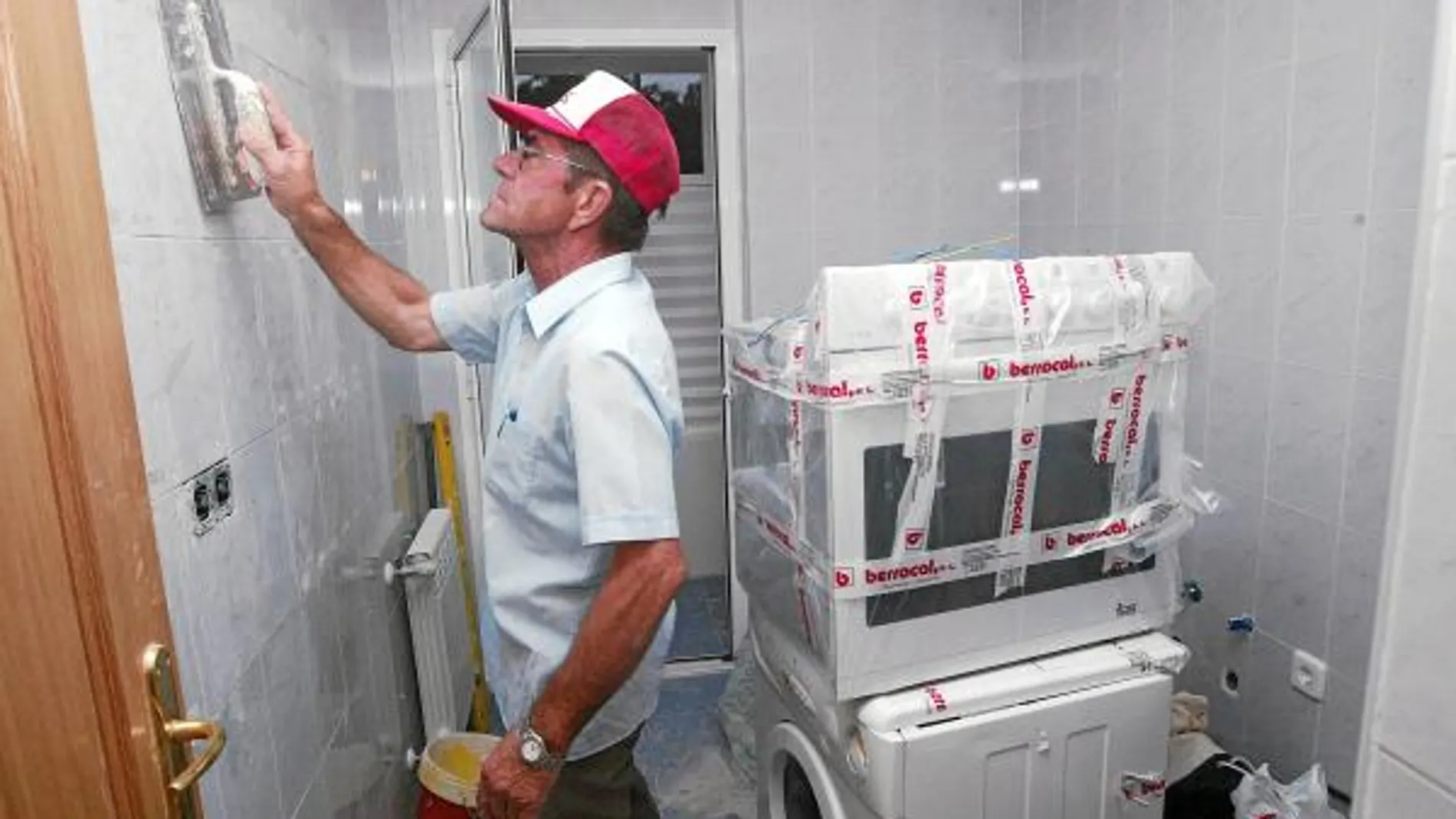 Un obrero pasa la llana por una cocina, durante las obras de rehabilitación de una vivienda
