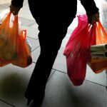 Una mujer lleva la compra en bolsas plásticas gratuitas