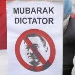 Una mujer sostiene una pancarta que reza «Mubarak, dictador»