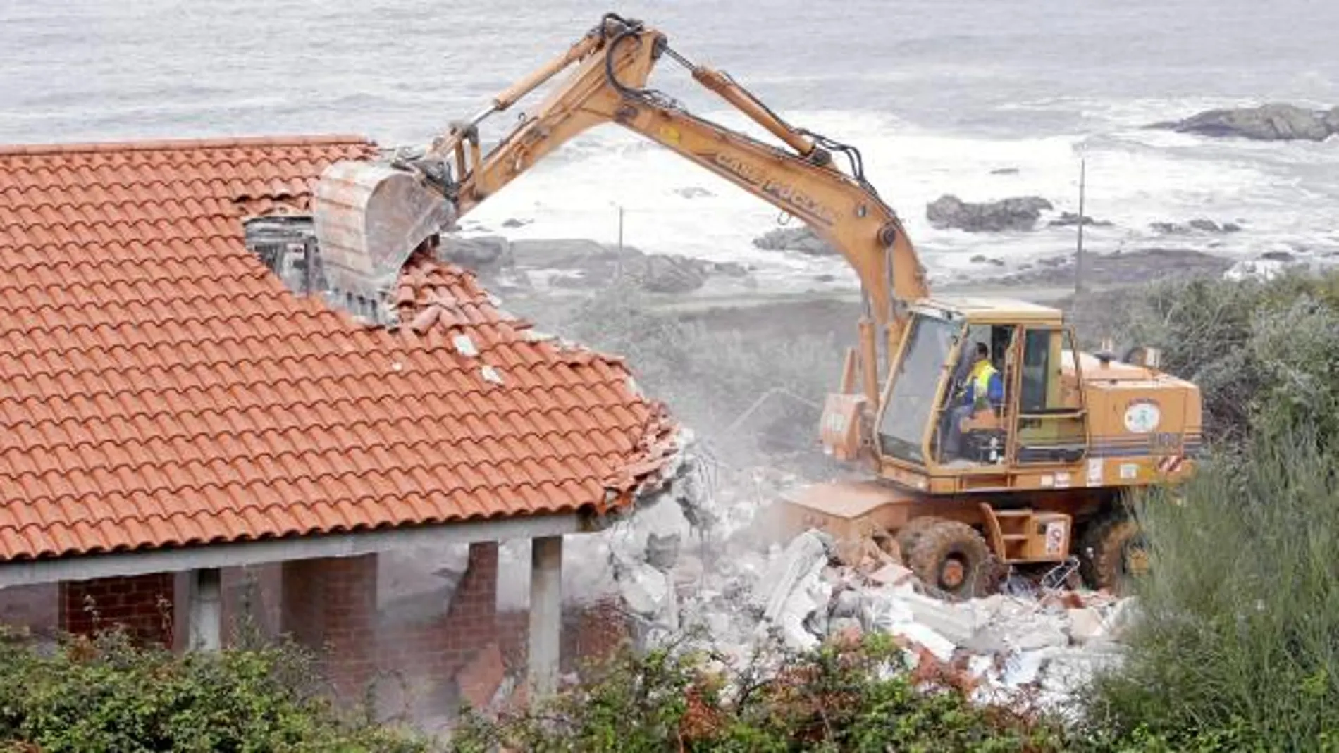 Una excavadora derriba una vivienda próxima a la playa