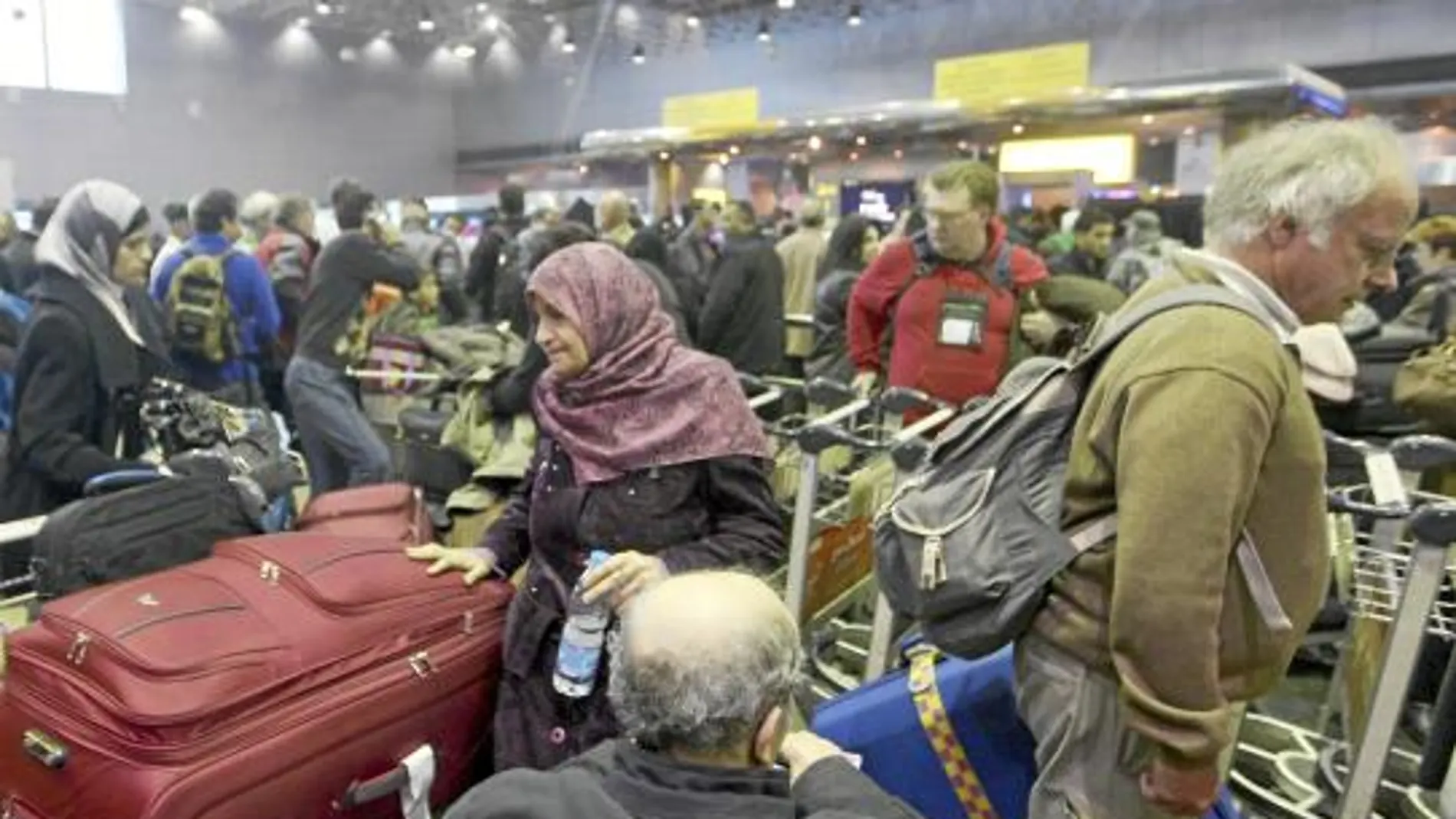 Varios pasajeros esperan a embarcar en un vuelo, ayer, en el saturado aeropuerto de El Cairo