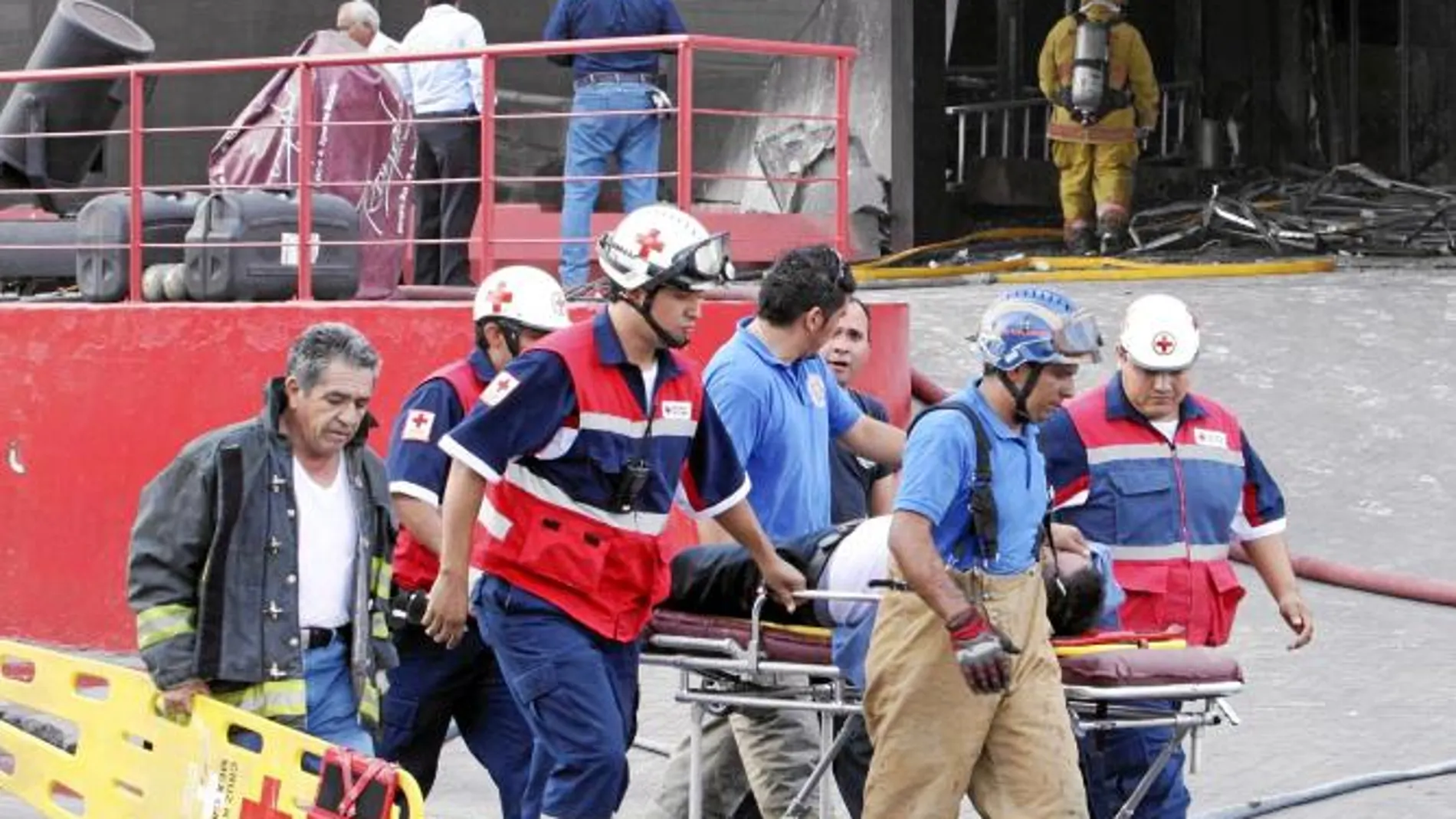 Varios bomberos y personal de rescate trasladan a un herido tras el ataque al Casino Royale de Monterrey, ayer