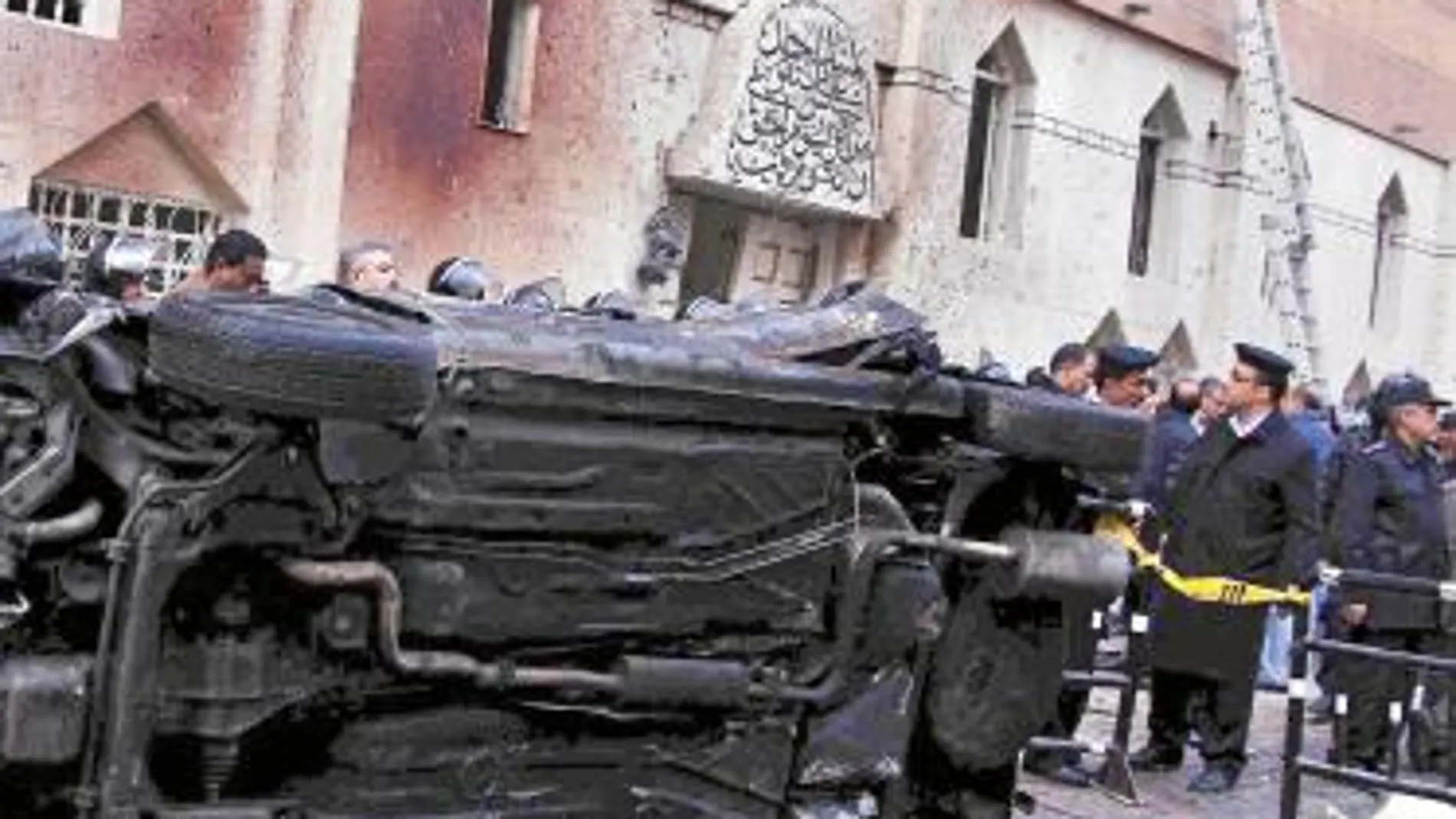 Policías egipcios montan un cordón de seguridad en torno a un coche destrozado en el atentado perpetrado en Alejandría el 31 de diciembre