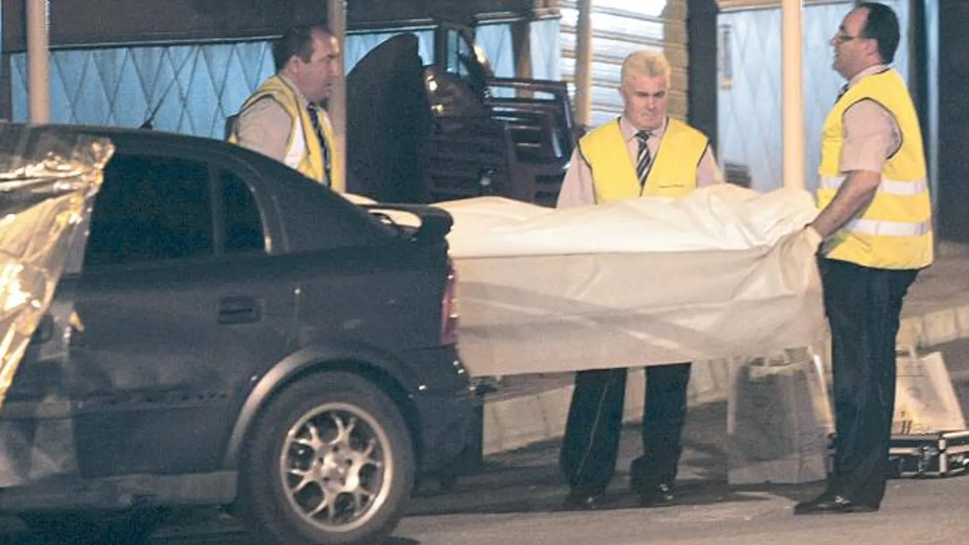 Unos operarios portan el cuerpo del asesinado en Castellón