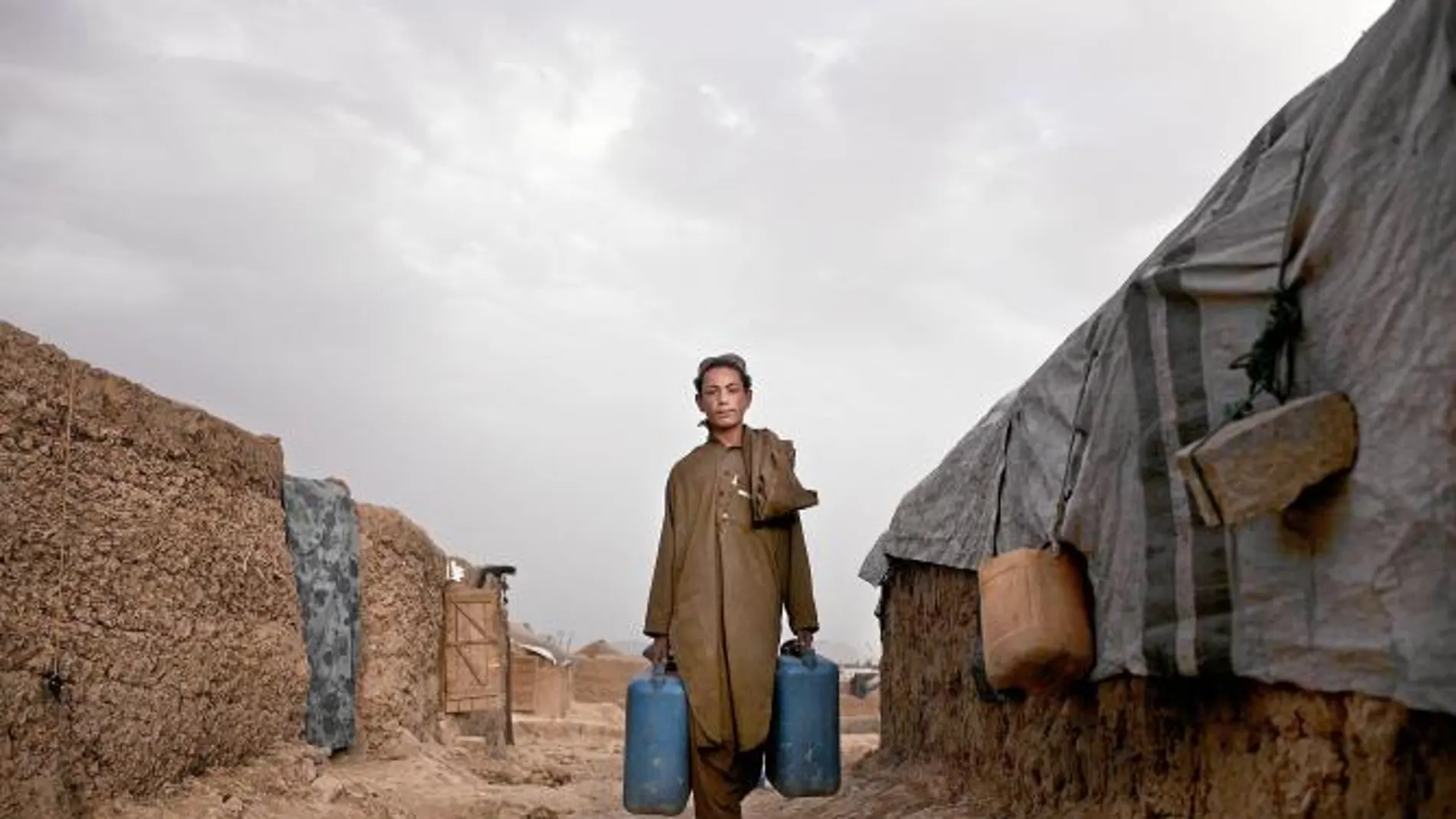 Un joven afgano porta unas garrafas en el campamento de refugiados