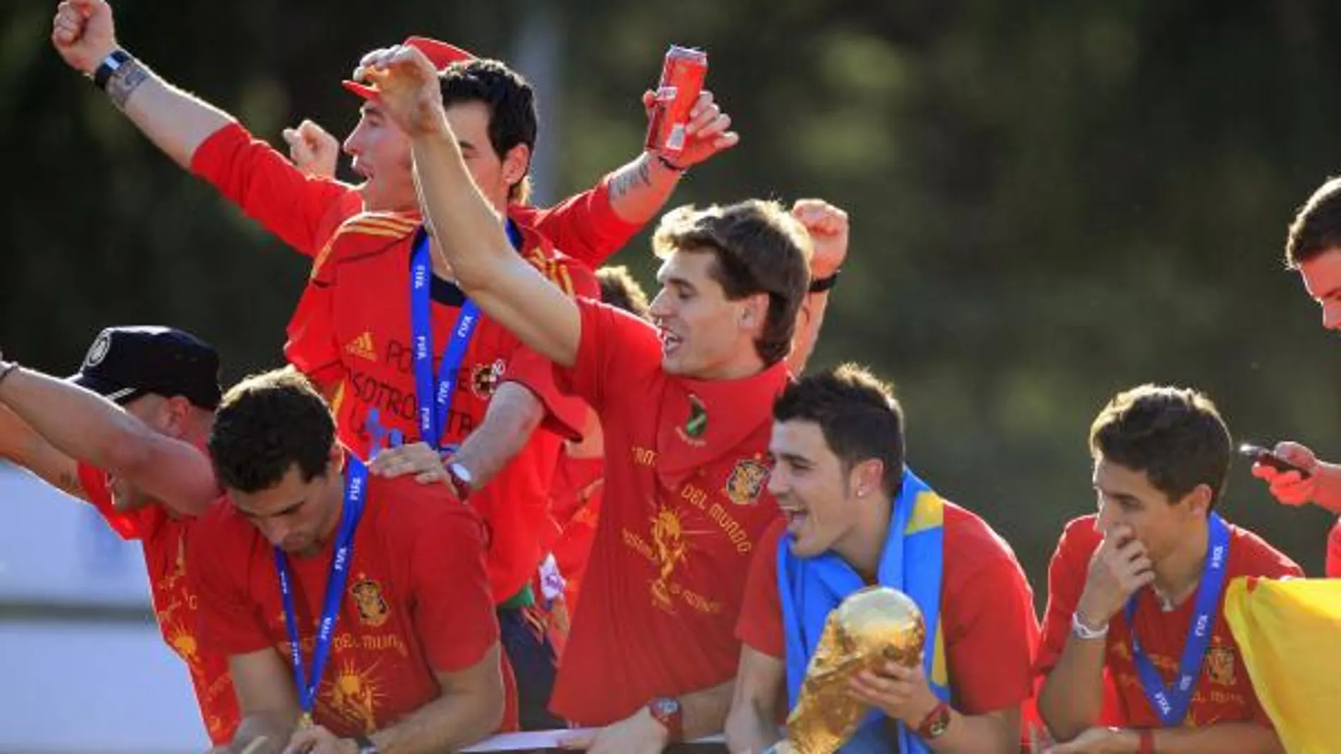 El delantero de la selección española de fútbol, David Villa, sostiene la Copa del Mundo junto a sus compañeros, en el autobús descapotable que les pasea por las calles de Madrid