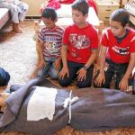 Un grupo de niños reza ante el cadáver de un rebelde muerto, ayer, en Misrata