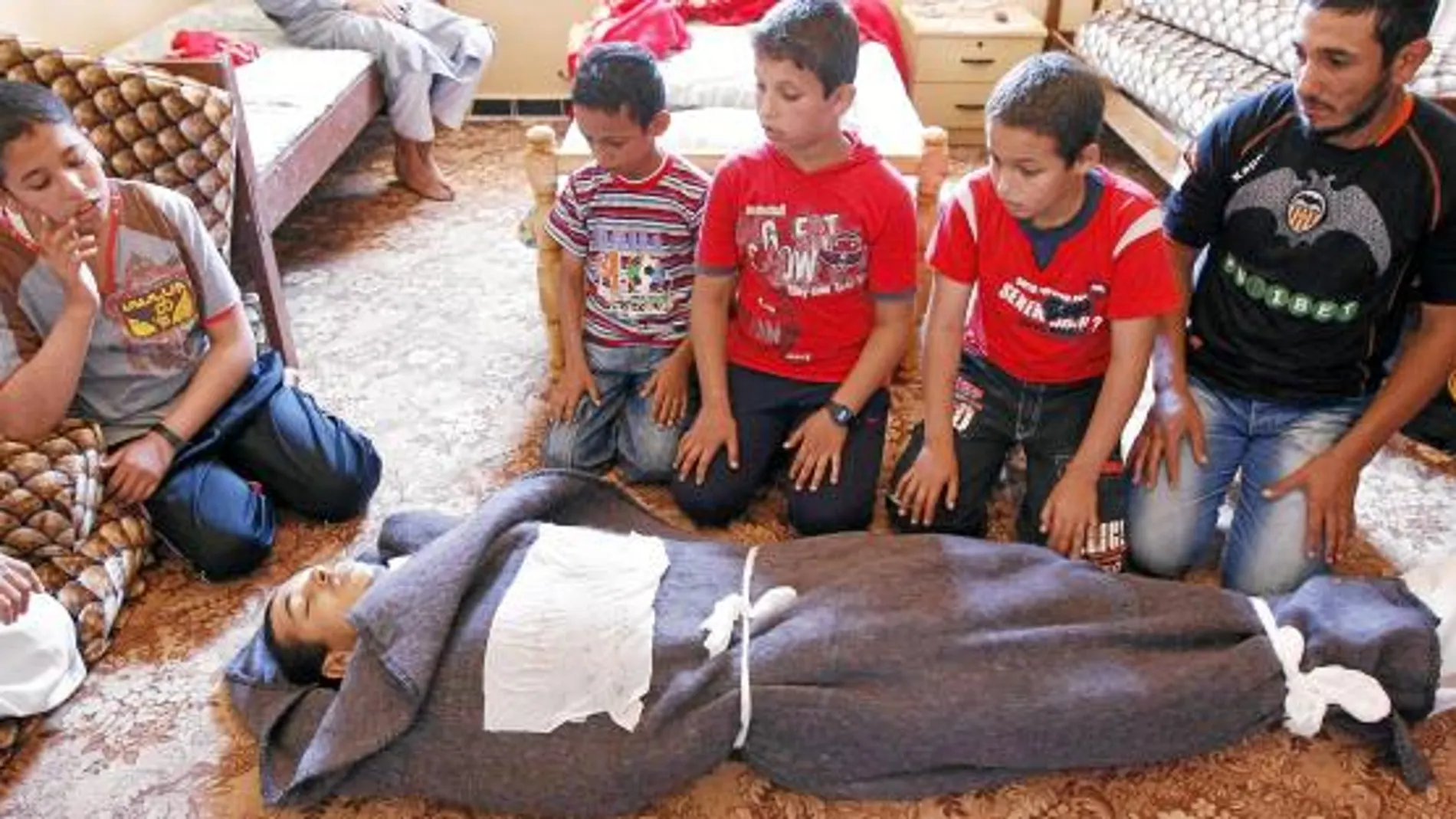 Un grupo de niños reza ante el cadáver de un rebelde muerto, ayer, en Misrata