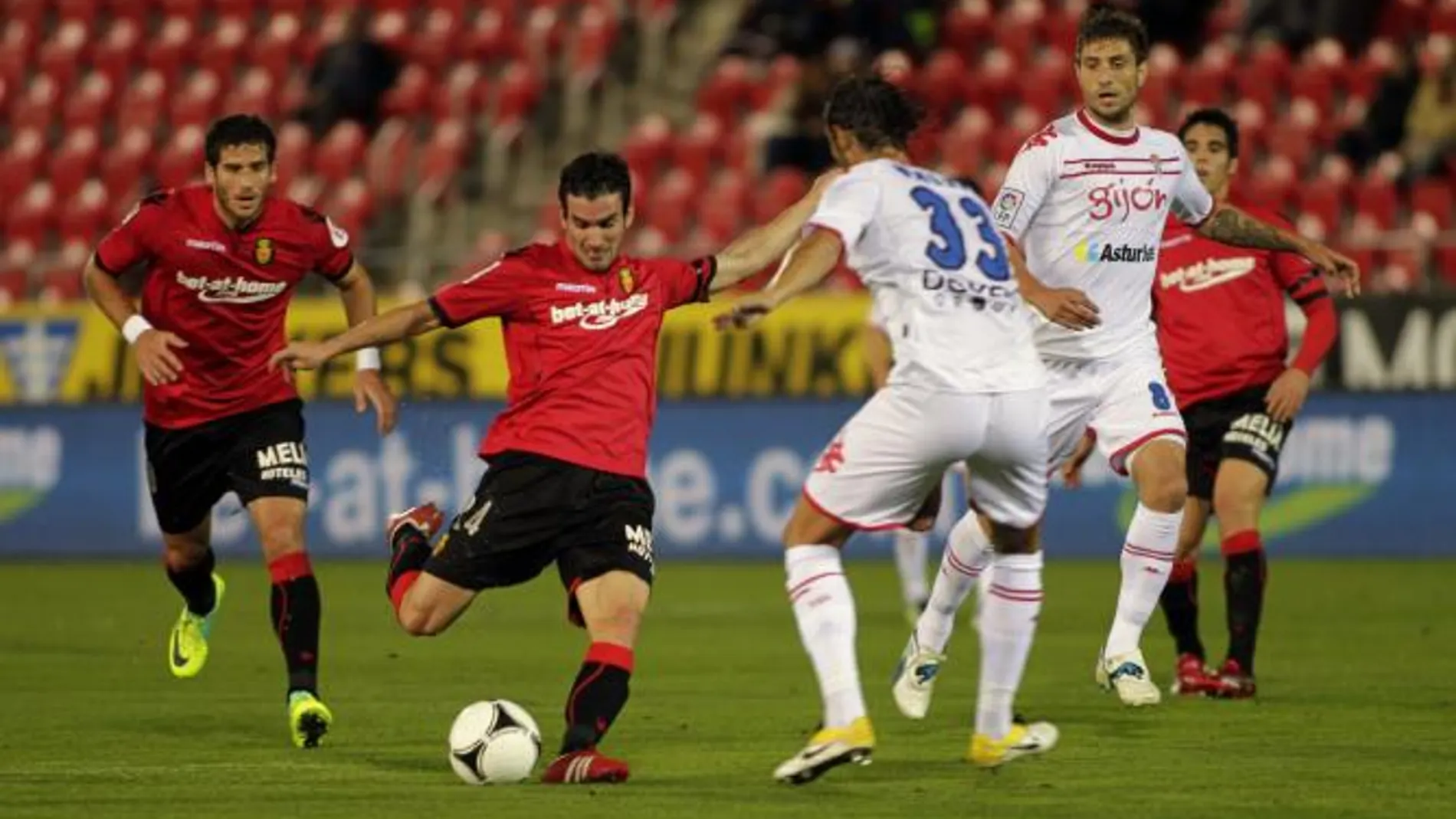 El delantero del RCD Mallorca, Alejandro Alfaro (2i), golpeal el balón ante el defensor del Sporting de Gijón