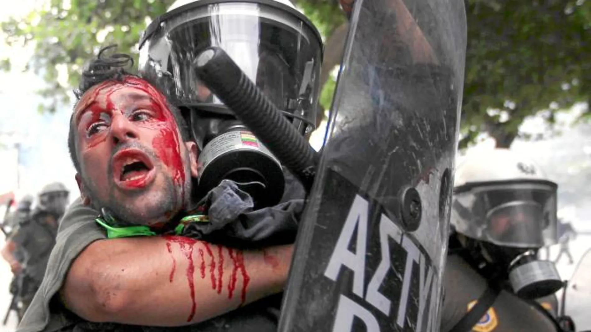 Un policía reduce a un manifestante durante los disturbios en Atenas con ataques a ministerios y diputados