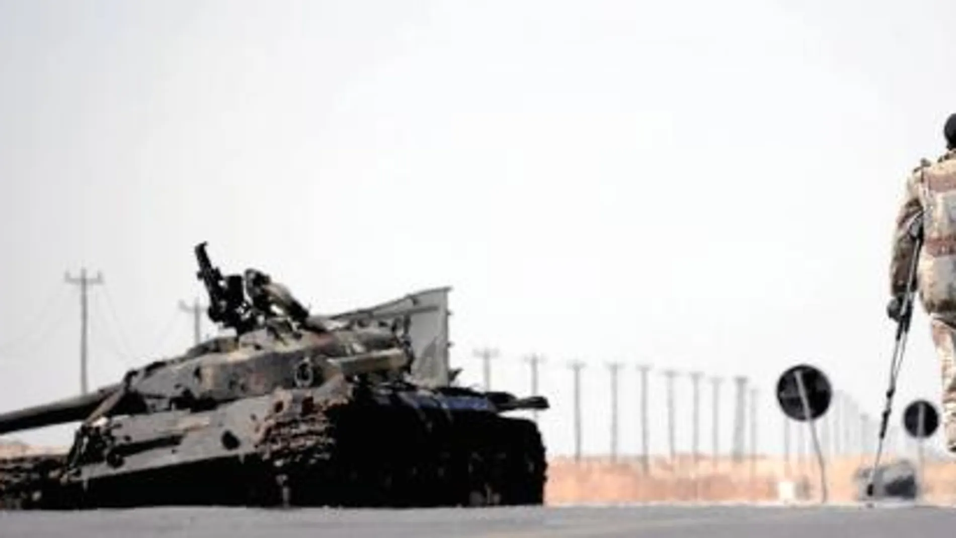 Un combatiente rebelde libio junto a los restos de un tanque entre Brega y Ajdabiya