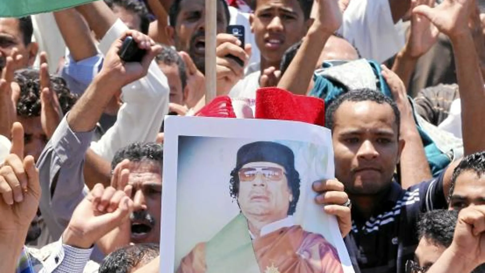 Partidarios del líder Muamar Gadafi con fotos del mandatario en una marcha después del rezo de los viernes.