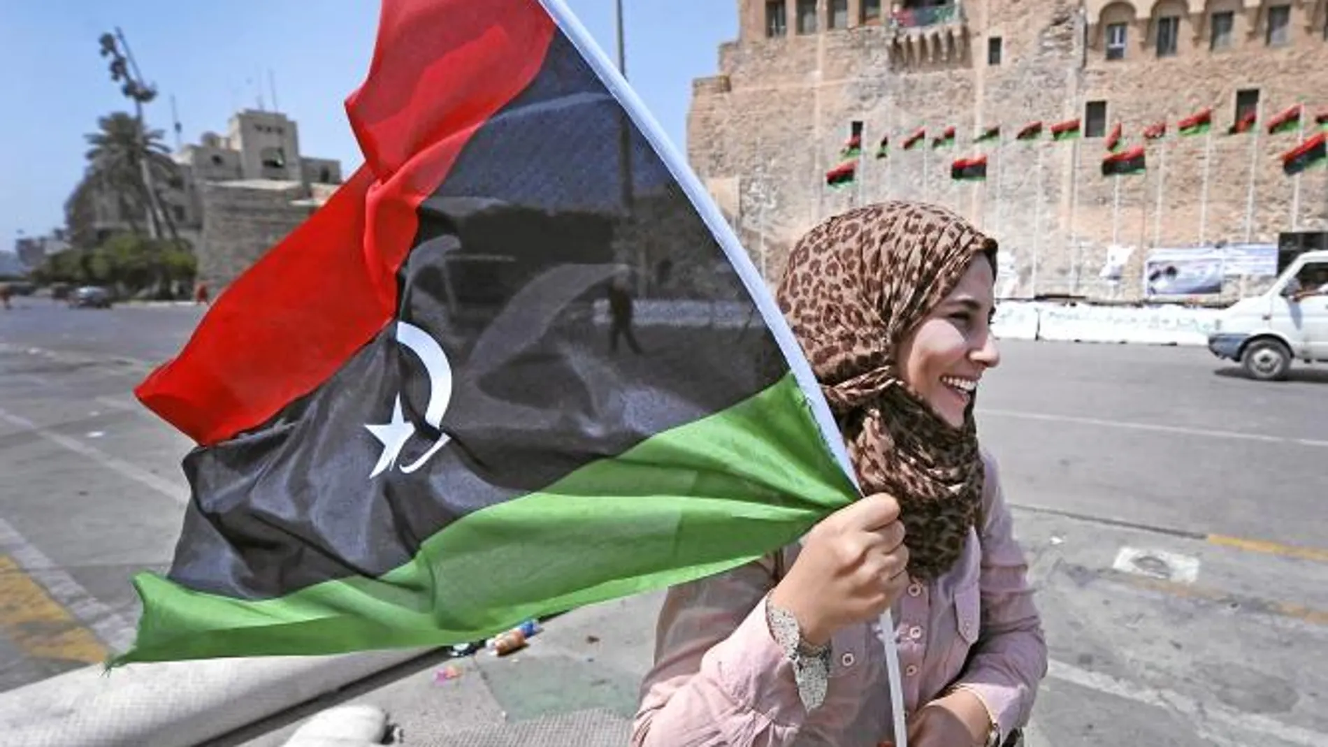 Una mujer ondea una bandera en la plaza de los Mártires de Trípoli