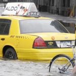 Un ciclista intenta avanzar en una calle inundada de Nueva York, ayer, junto a un taxi inmovilizado por el agua