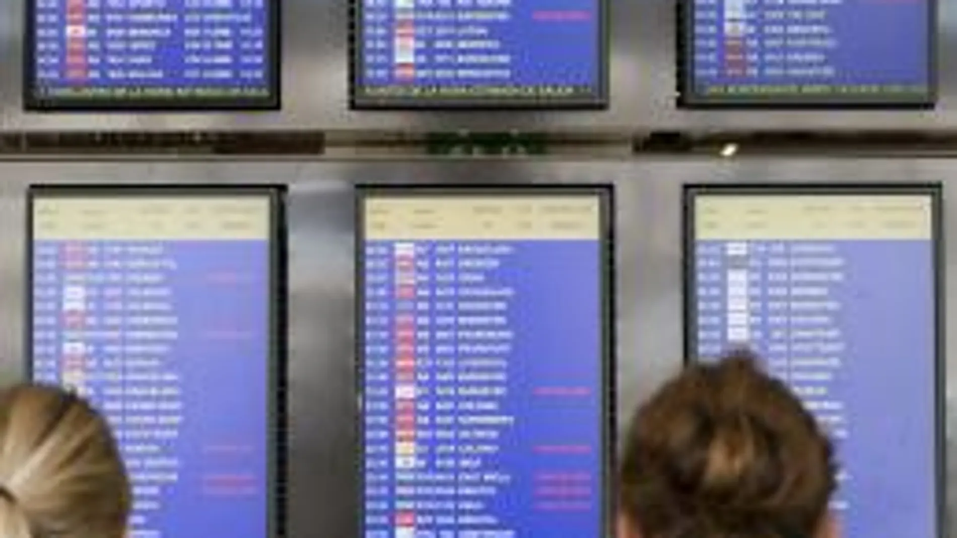 Varias personas observan un panel informativo del aeropuerto de Palma