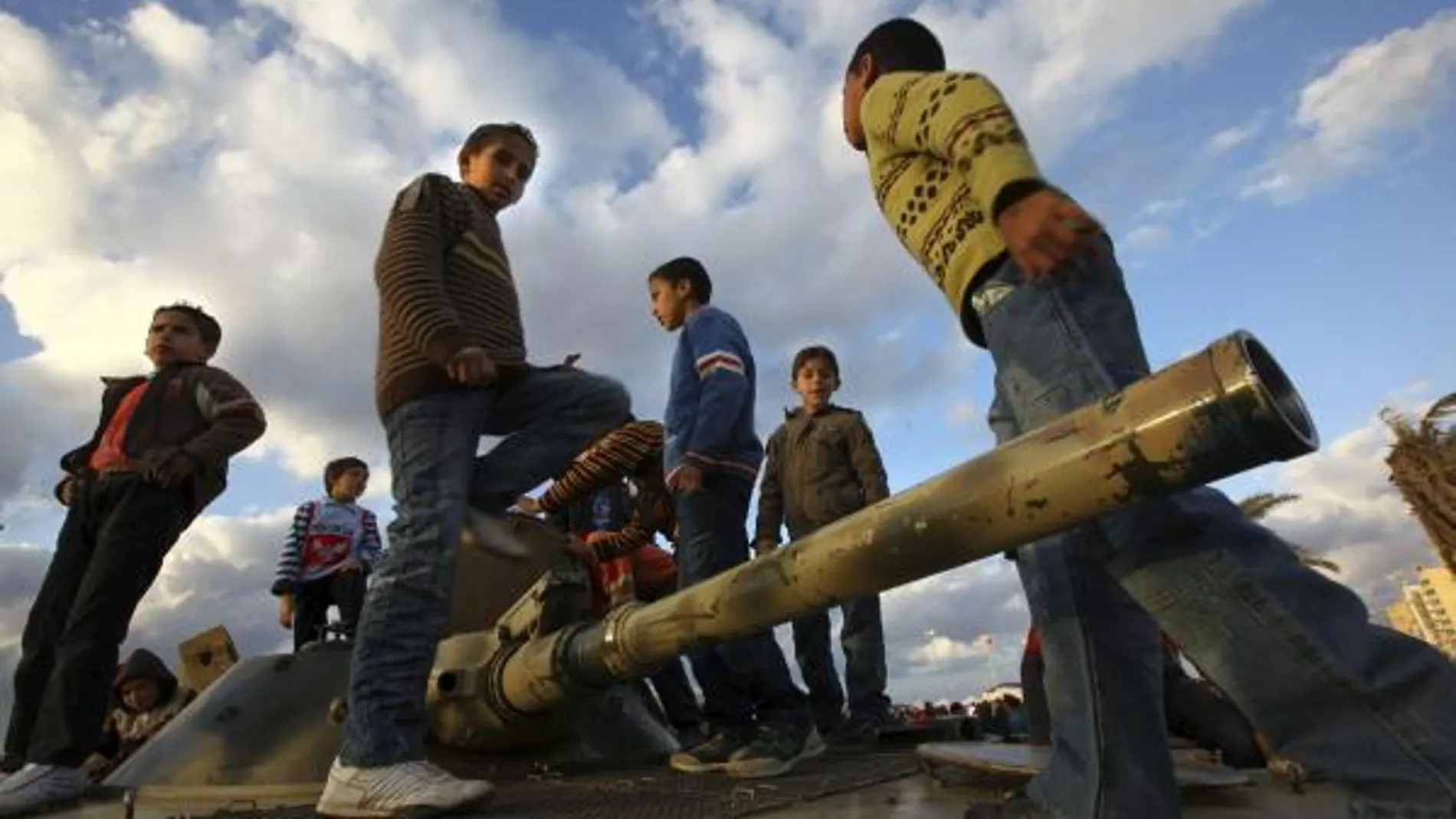 Varios niños juegan encaramados a un tanque en la ciudad de Benghasi