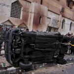 Policías egipicios montan un cordón de seguridad alrededor de un coche calcinado tras el atentado con coche bomba registrado frente a la iglesia cristiana de Al Qidiseen (Los Santos) de la ciudad de Alejandría (Egipto), a la salida de los oficios religios