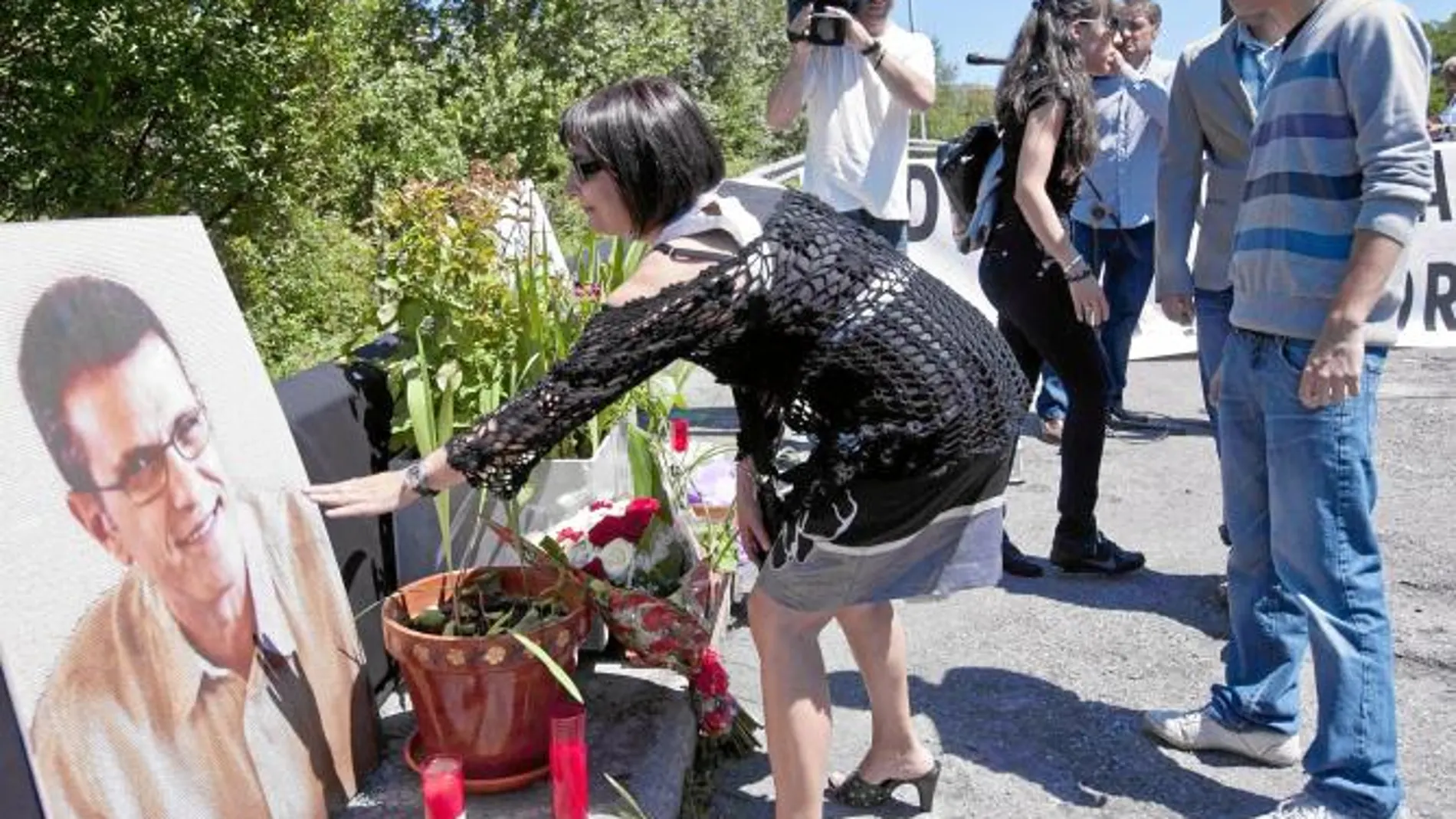 La viuda y sus dos hijos depositan unas flores en el lugar del asesinato