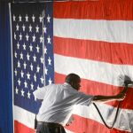 Un operario plancha la bandera para un acto de la jornada electoral