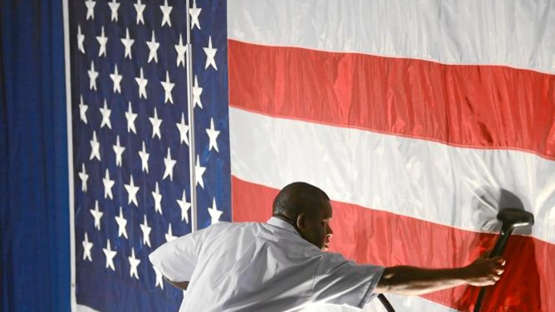 Un operario plancha la bandera para un acto de la jornada electoral