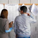 Dos jóvenes gallegos comprueban las listas del censo electoral para saber en qué mesa les corresponde votar