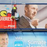 Dos trabajadores sustituyen los carteles electorales por un anuncio de juguetes.