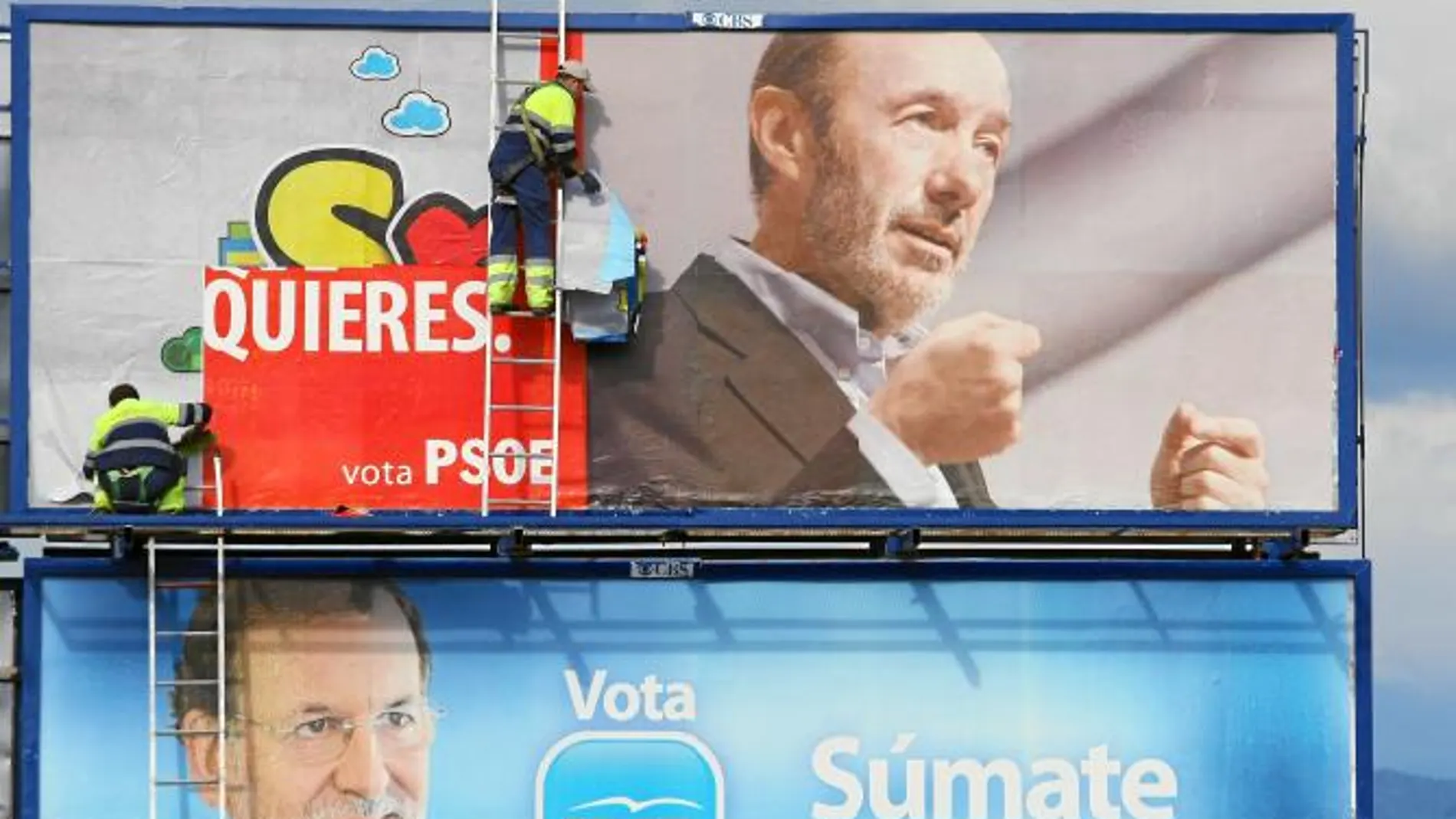Dos trabajadores sustituyen los carteles electorales por un anuncio de juguetes.