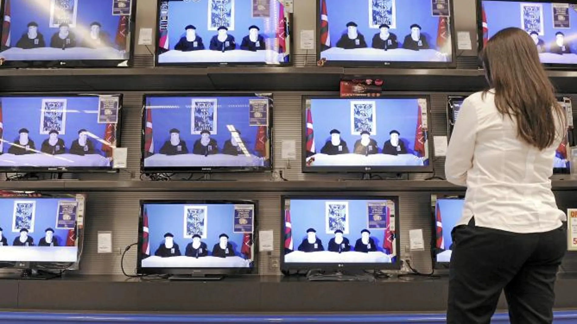 Una mujer ve en el escaparate de una tienda de televisiones el momento en el que los etarras leen el comunicado