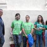 El presidente de la Junta, ayer en Cádiz en el inicio del curso universitario al paso de unos alumnos con camisetas de protesta