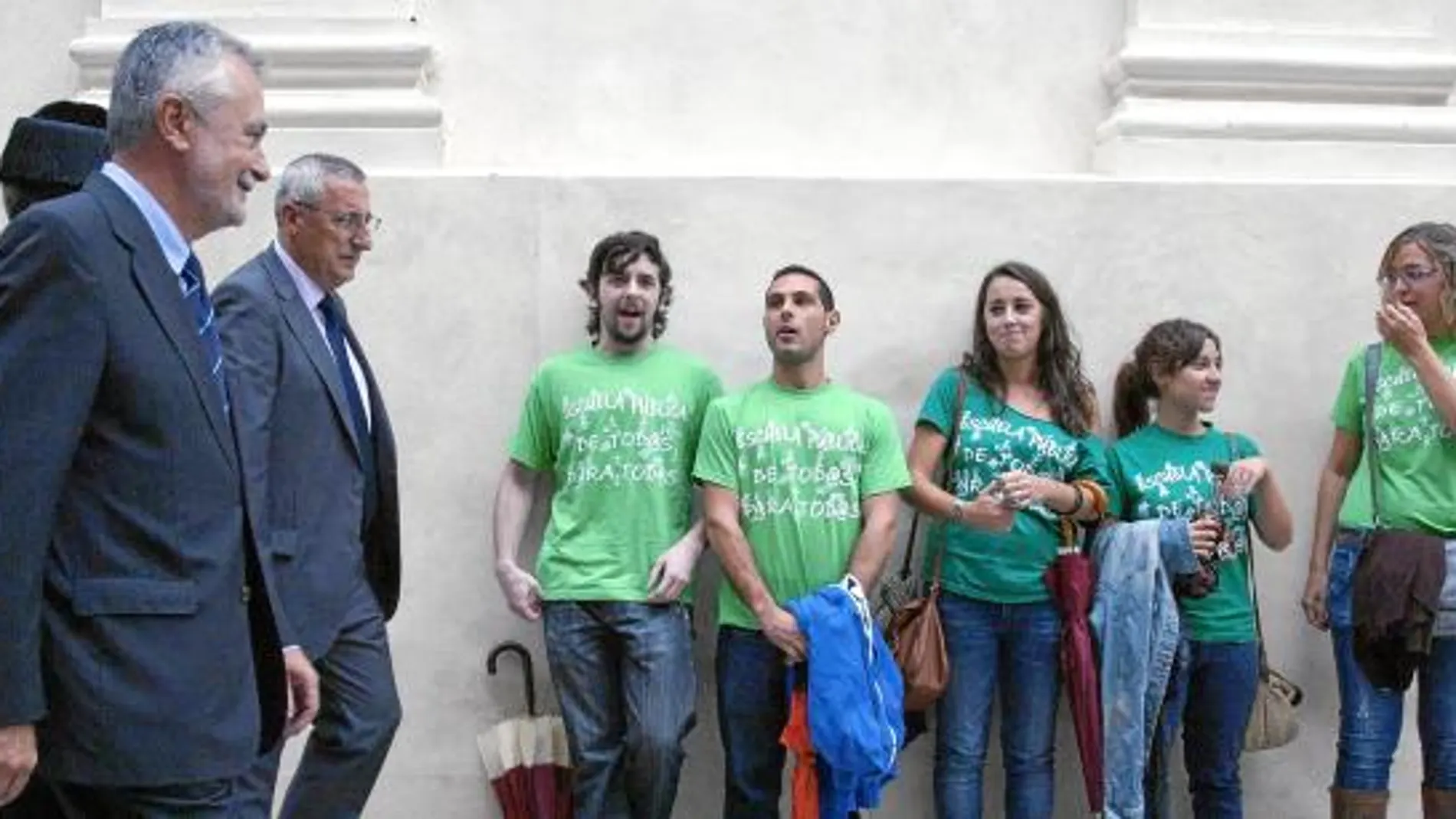 El presidente de la Junta, ayer en Cádiz en el inicio del curso universitario al paso de unos alumnos con camisetas de protesta