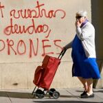 Una mujer pasa, ayer en Barcelona, ante una pintada en la que se lee: «Pagad vuestras deudas, ladrones»