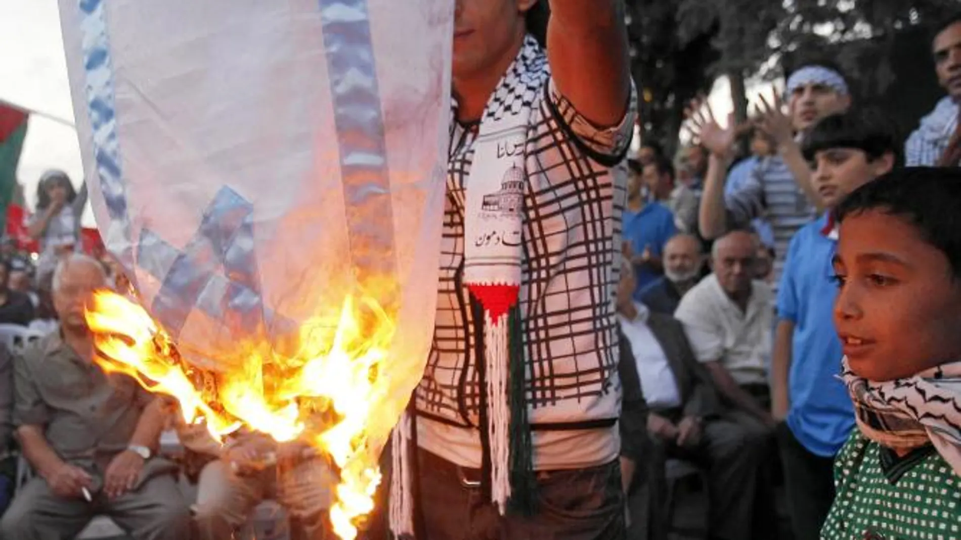 Activistas palestinos y jordanos queman una bandera israelí frente a la sede de la ONU en Ammán, ayer