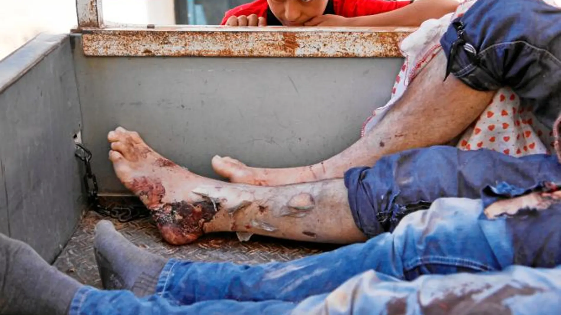 Un niño mira los cadáveres hallados en la batalla de Alepo