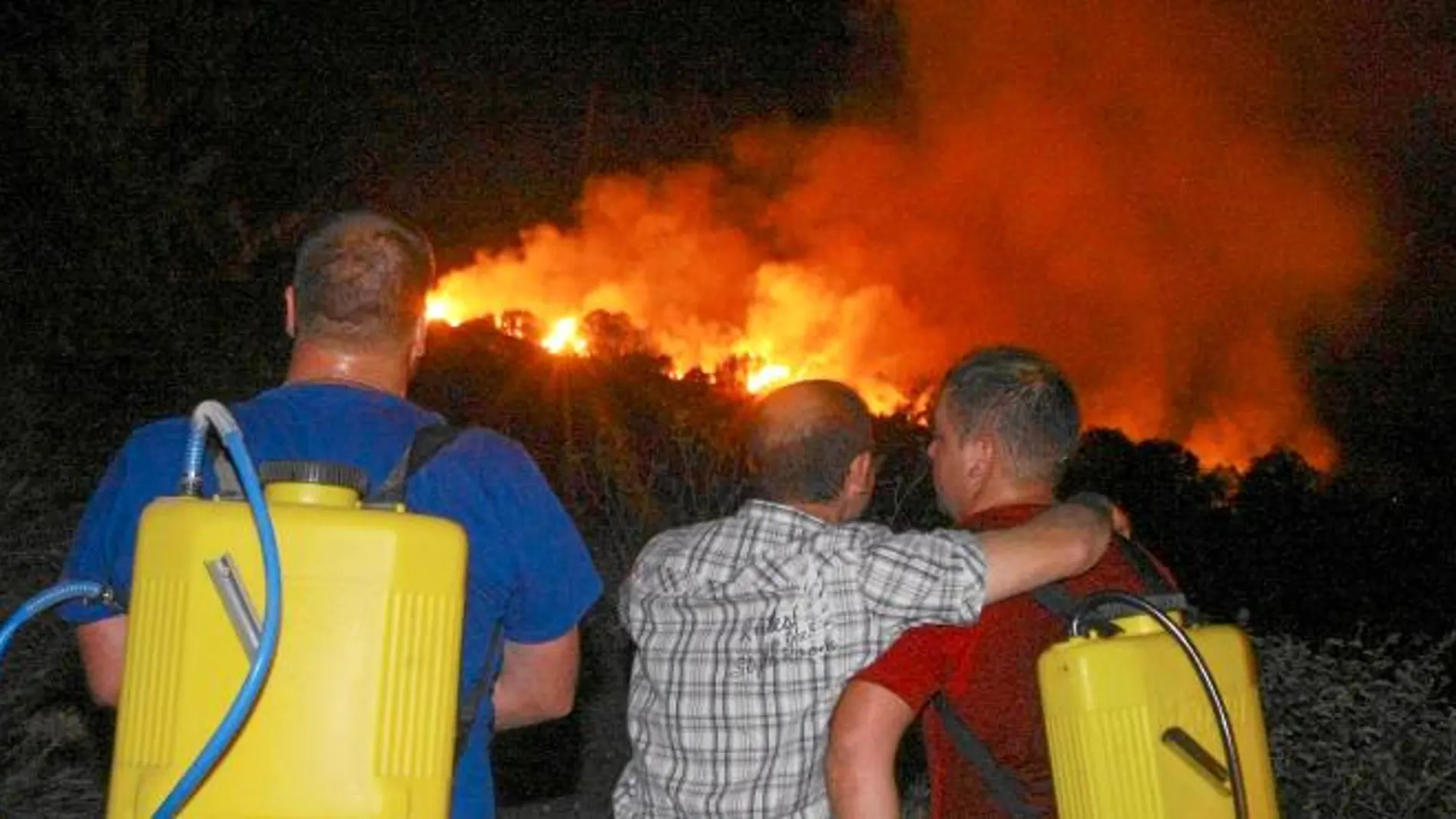 Varios vecinos de la localidad berciana de Villar de los Barrios, cercana a Ponferrada, observan, impotentes, el avance de las llamas cerca de sus casas en el incendio que se produjo el pasado 23 de julio