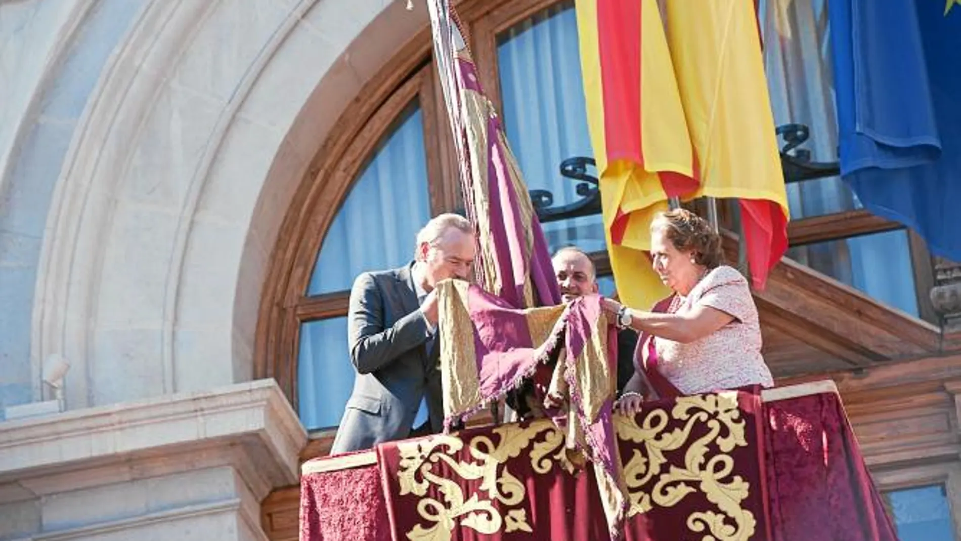 El presidente de la Generalitat, Alberto Fabra, besa la Real Senyera en el balcón del Ayuntamiento, ante la atenta mirada de Rita Barberá