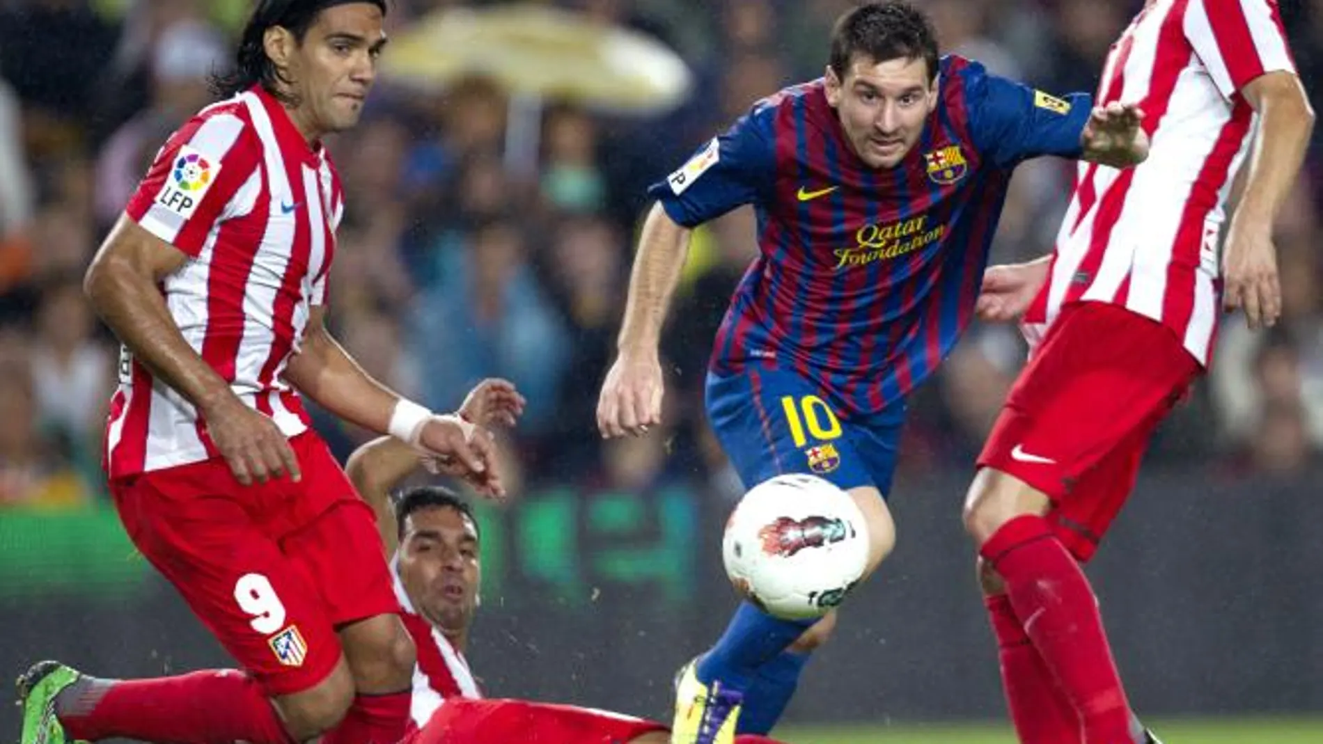 El delantero argentino del FC Barcelona, Lionel Messi (2d), se marcha de los jugadores del Atlético de Madrid: el delantero colombiano Radamel Falcao (i), el delantero turco Arda Turan (suelo) y el centrocampista Gabi Fernández (d)