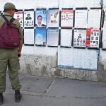 Un soldado (i) observa unos carteles electorales en Túnez (Túnez) durante la jornada de reflexión