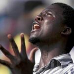 Un joven africano reza durante la eucaristía del Papa en el estadio La Amistad de Cotonú