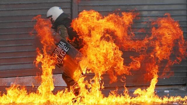 Un policía huye del fuego provocado por un cóctel molotov lanzado por los manifestantes