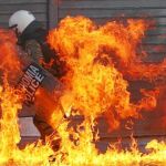 Un policía huye del fuego provocado por un cóctel molotov lanzado por los manifestantes
