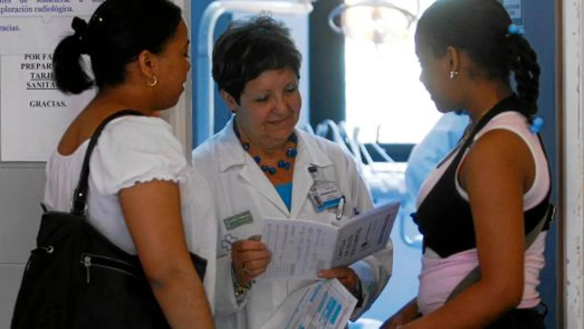 Una médica atiende a dos inmigrantes