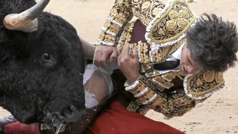 El charro, volteado, se agarra al pitón del serio primero de Samuel Flores