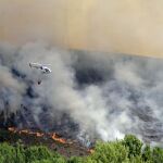 Un helicóptero sobrevuela una zona incendiada cercana al pueblo de A Veiga de Cascallá