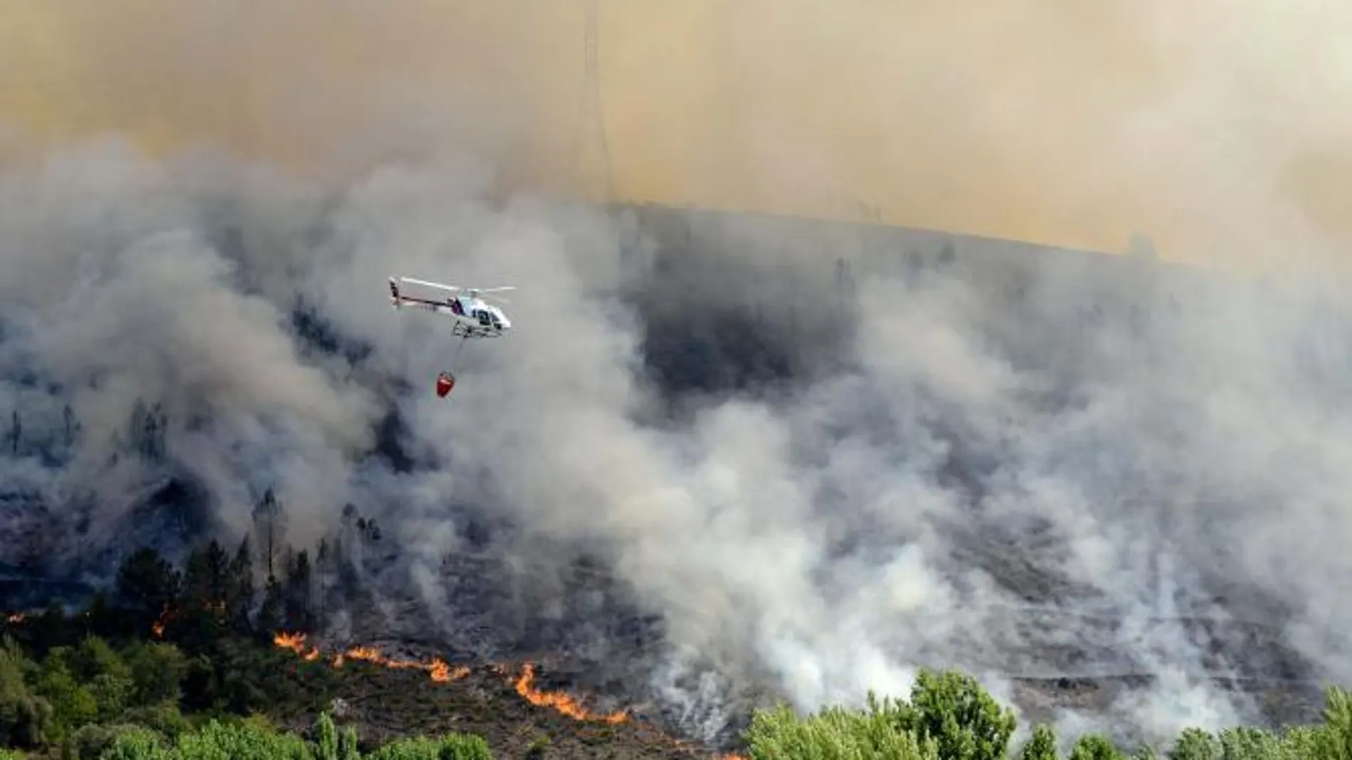 Un helicóptero sobrevuela una zona incendiada cercana al pueblo de A Veiga de Cascallá
